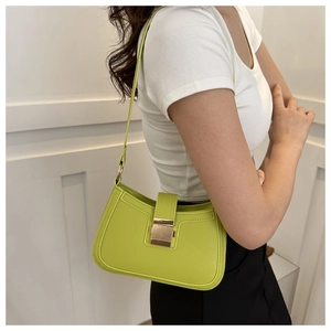 Close-up of lime green baguette shoulder bag with gold clasp shown on model