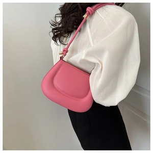 Détail du sac à main rose minimaliste avec silhouette incurvée et boucles dorées