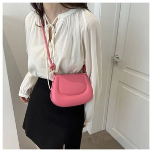 Vue détaillée d'un sac selle rose avec sangle à nœud et détails dorés