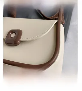 Detail of white PU leather shoulder bag with brown trim and coffee resin buckle