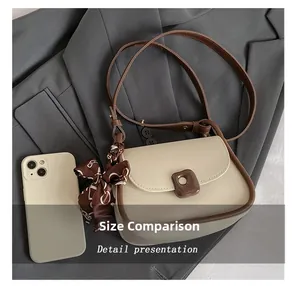 Detail presentation of color-block saddle bag next to phone for size comparison