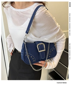 Detail of dark blue denim shoulder bag featuring silver metal chain and rivet studs