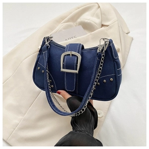 Detail of dark blue denim shoulder bag with silver buckle, rivets and white stitching