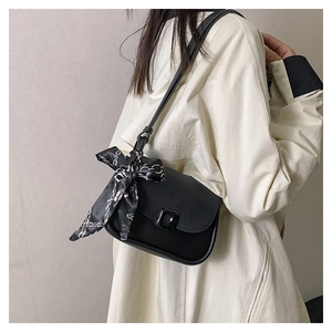 Detail of black crossbody bag featuring a matte leather finish and decorative chain silk scarf