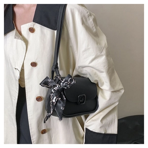 Detail of black mini crossbody bag featuring a silk scarf wrapped around the handle strap