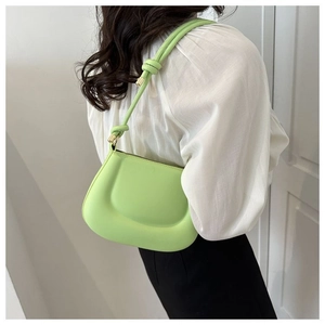 Détail d'un sac à bandoulière vert clair bouffant avec des lanières tressées mates