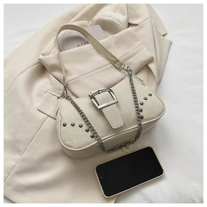 Detailed shot of cream canvas shoulder bag featuring silver metal buckle and chain strap