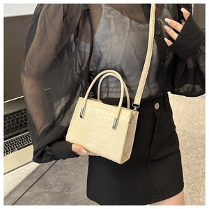 Dettaglio mini borsa crema goffrata coccodrillo con tracolla sottile e doppi manici