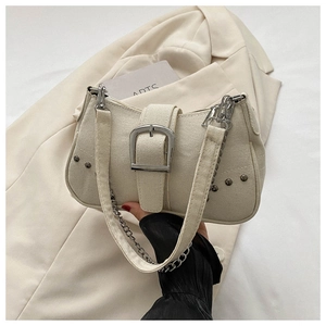 Detailed texture of beige canvas underarm bag with silver buckle and metallic rivets