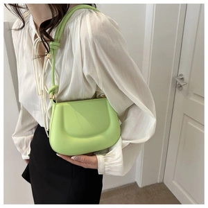 Détail du sac vert fluo avec gaufrage en U et bandoulière à nœud pour un look moderne