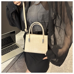 Dettaglio borsa beige con stampa coccodrillo, finiture argento e doppi manici corti