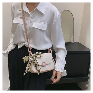 Detail of cream crossbody bag with pink edges and elegant silk scarf accessory