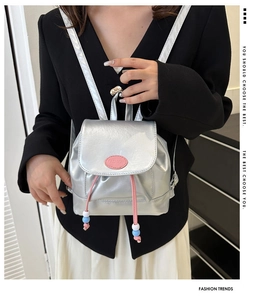 Detail eines silbernen Mini-Rucksacks mit rosa Kordelzug und Metallic-Finish-Struktur