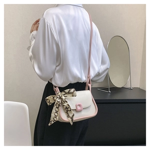 Detail view of stylish cream shoulder bag with pink trim and elegant floral silk scarf