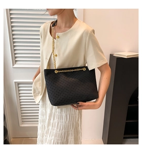 Detalle del bolso tote acolchado negro con cadena dorada llevado por una modelo con estilo
