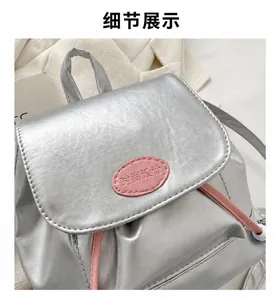 Detail eines silbernen Rucksacks mit rosa Kordelzug und rosa Fashion-Lederetikett