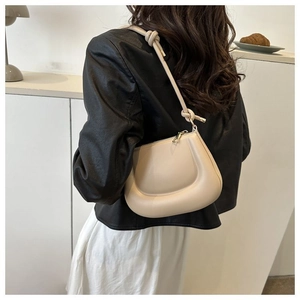 Chic sac hobo beige en demi-lune avec bandoulière nouée porté par un mannequin en décor épuré