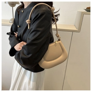 Gros plan du sac demi-lune crème avec bandoulière nouée et fermeture éclair dorée élégante