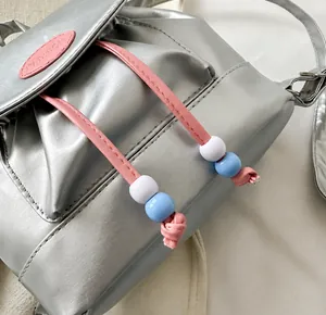 Details des silbernen Metallic-Rucksacks mit rosa Kordelzug und bunten Zierperlen