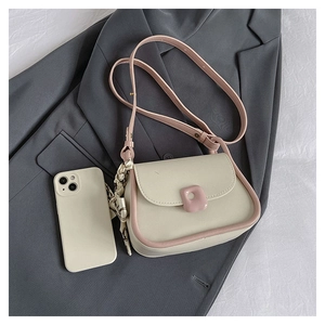 Top view of cream crossbody bag with pink trim next to a smartphone for size reference