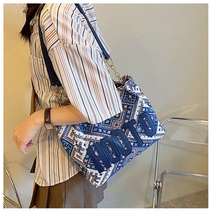 Detail of woven tote bag with HOOTO embossed letters and metallic chain strap