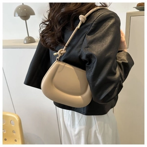 Vue latérale d'un sac demi-lune crème avec une large bandoulière en cuir noué élégante