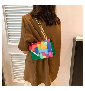 Detail of colorful geometric patchwork crossbody bag with golden chain strap on a model