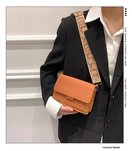 Detail of orange square crossbody bag with wide geometric patterned shoulder strap