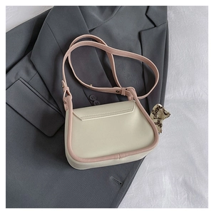 Detail view of cream leather mini bag with silk scarf on a dark grey suit jacket