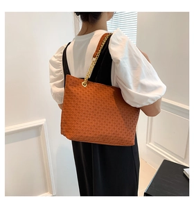 Detalle del bolso tote trenzado café con correa de cadena dorada en modelo de espalda