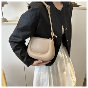 Détail du sac hobo minimaliste en cuir crème avec bandoulière nouée et boucles dorées