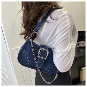 Detail of dark blue denim shoulder bag featuring silver rivets and metal chain strap