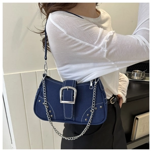 Detail of blue denim shoulder bag with silver hardware and rivet studs on model