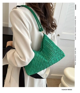 Détail du sac à bandoulière plissé vert avec texture ondulée et forme demi-lune moderne