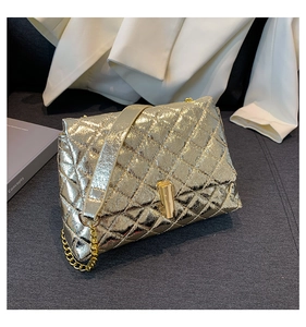 Detail of metallic gold quilted handbag with elegant chain strap and turn-lock closure
