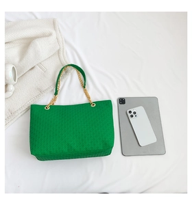 Detalle del bolso tote verde trenzado con asas dobles de cadena dorada y gran espacio