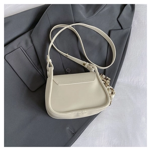 Detail of a cream crossbody bag with a silk scarf accessory on a dark blazer background