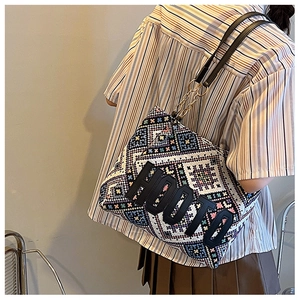 Close-up of geometric woven tote bag with HOOTO patch and chain strap on shoulder