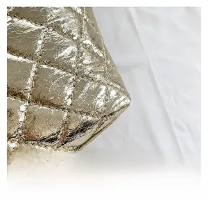 Vue macro détaillée du tissu métallisé doré matelassé et des coutures fines du sac