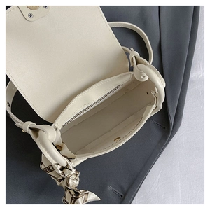 Detail view of cream mini crossbody bag showing internal zipper pocket and magnetic buckle