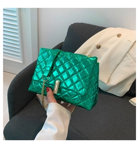 Detail of metallic green quilted crossbody bag with golden twist lock and chain strap