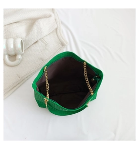 Vista detallada del bolso verde con cadenas doradas y textura trenzada de alta calidad