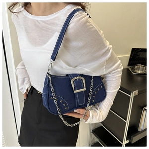 Detail of dark blue denim underarm bag featuring silver chain and metal buckle on model