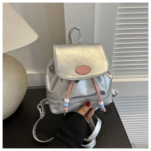 Nahaufnahme eines silbernen Mini-Rucksacks mit rosa Logo und bunten Perlen-Kordelzügen