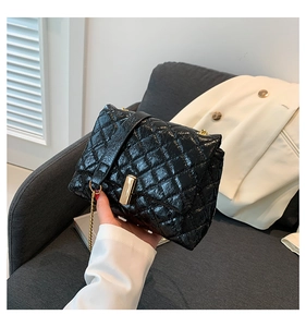 Detail of glossy quilted black crossbody bag with golden clasp and chain strap