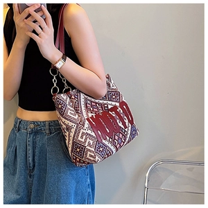 Detail of woven tote bag with geometric patterns, red leather straps and gold metal chain