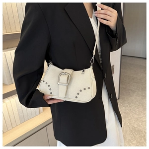 Beige vintage underarm bag with silver studs and large buckle shown on shoulder