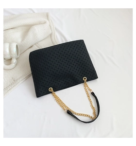 Detalle del bolso tote trenzado negro con diseño geométrico y correa de cadena dorada