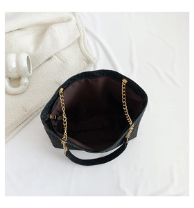 Vista superior de un gran bolso tote negro grabado con cadena dorada y detalle de cremallera