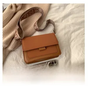 Close-up of brown faux leather crossbody bag with geometric pattern wide woven strap